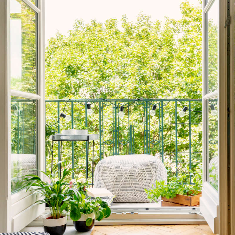 Das Bild zeigt den Blick aus einer Wohnung mit geöffnetem Balkonfenster auf den Balkon.