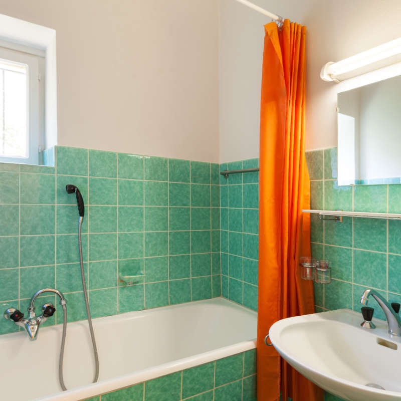 Das Bild zeigt ein gefliestes Bad mit Waschbecken und Badewanne